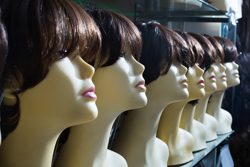 Mannequins with brunet style wigs on shelves of hair salon