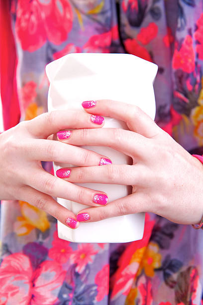 Female hands with coloured nails holding small vase stock photo