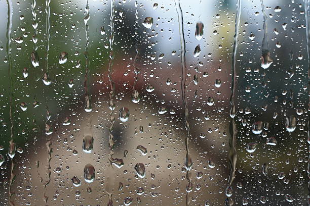 istock Rain drops on window with house and church in background 534034656