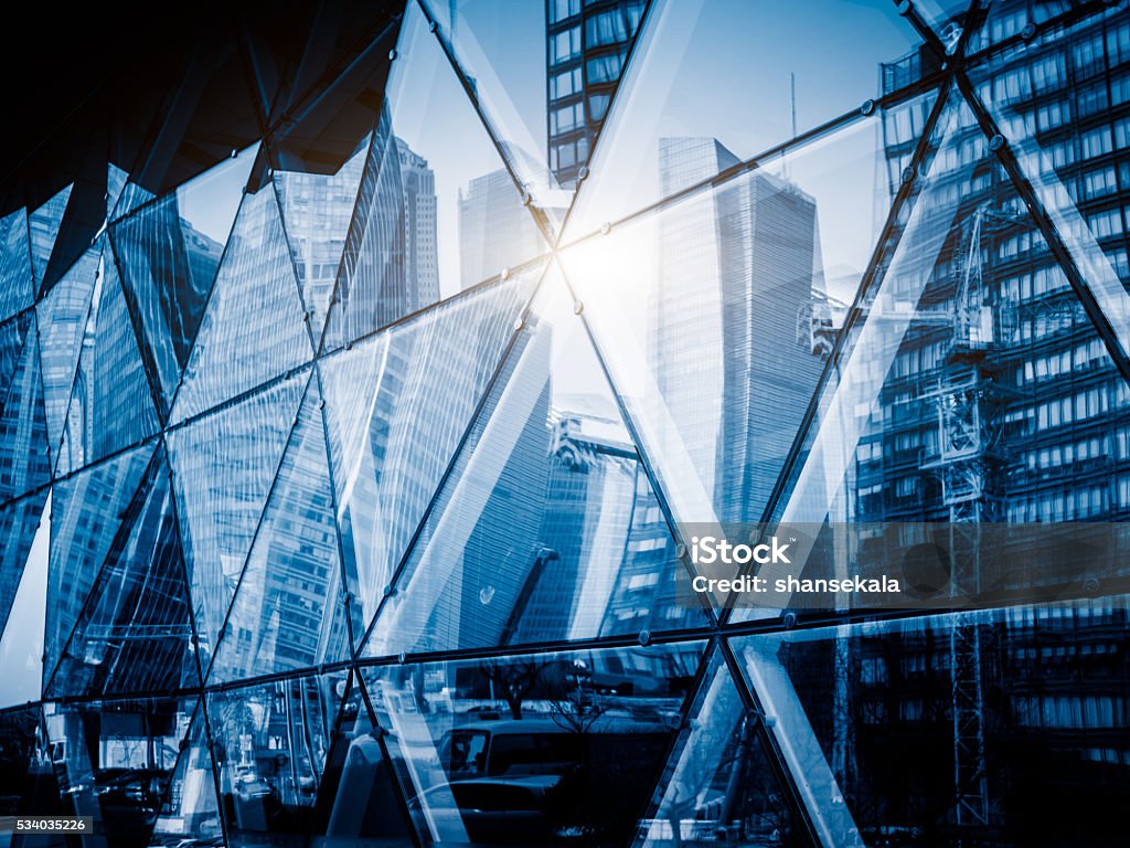 View of a modern glass skyscraper reflecting the blue sky View of a modern glass skyscraper reflecting the blue sky,blue toned image. Abstract Stock Photo