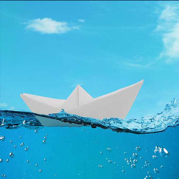 istock paper boat floating among the waves in the ocean 534035801