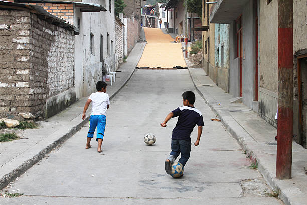 Magdalena, Peru - May 18, 2016: Two boys practice soccer moves as corn kernels dry in the street in front of them in Magdalena, Peru on May 18, 2016