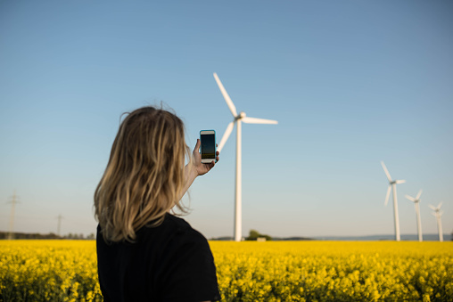 A young man taking a selfie in front of wind turbine on the field in Germany