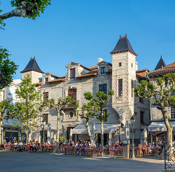 Saint Jean de Luz France - May 20 2016: People enjoying a bar terrace on Place Louis XIV of Saint-Jean de Luz with Maison Louis XIV in background.