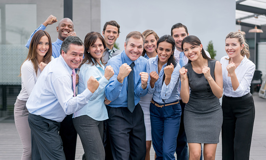 Successful group of business people celebrating at the office with arms up