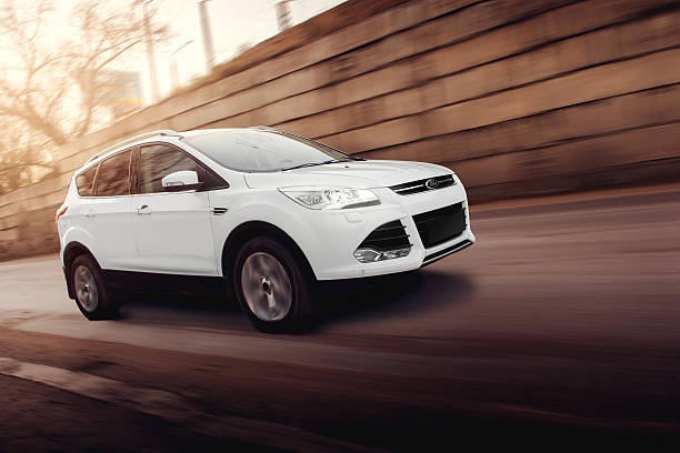 Saratov, Russia - November 25, 2014: White car Ford Kuga fast drive on road in the city at sunset
