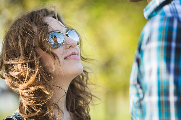 American couple in sunglasses walking in the park. Man and woman hugging in the park.