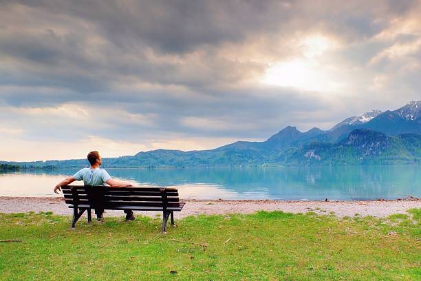istock Alone  man sits on bench at mountain lake. Man relax 534048816
