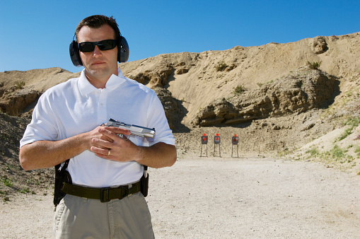 Man holding hand gun at firing range, portrait