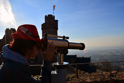 Mixed race teenage girl looking into a telescope out into a European city