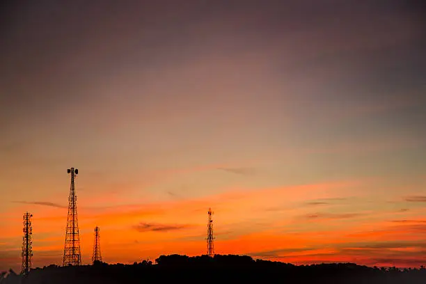 Radio mast and antenna silhouettes over a orange sunset in Goa, India