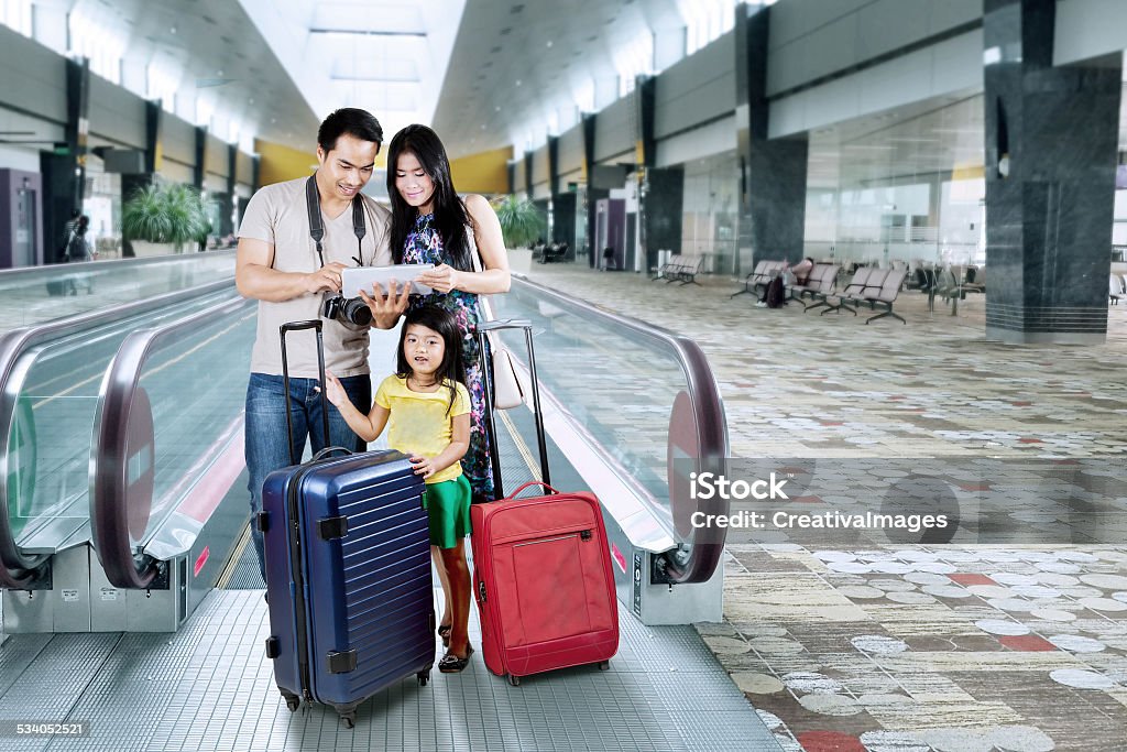 Happy family looking a map on tablet Asian family doing holiday trip and looking a map on the digital tablet at the airport hall Family Stock Photo