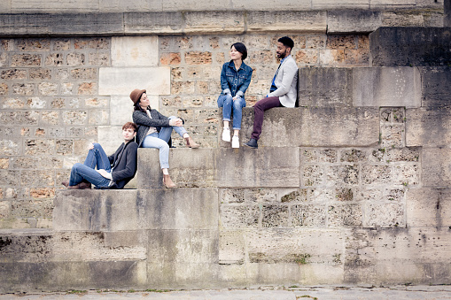 Multi-ethnic group of friends having fun in Paris along the Seine river, near Notre Dame Cathedral.