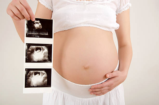 Close up on pregnant belly with baby's ultrasound. stock photo