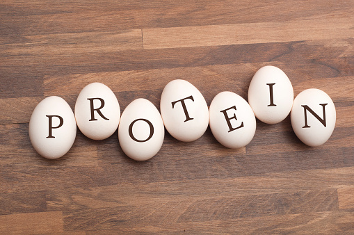 Protein Spelled out on a group of eggs placed on a wooden table.