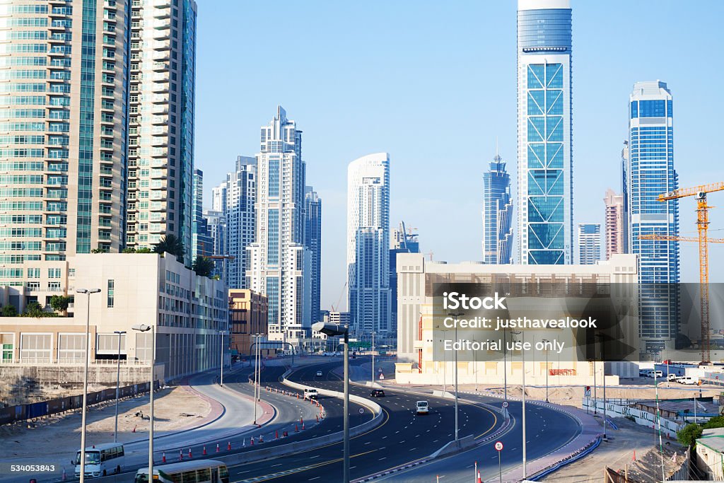 Growing skyline of Dubai Dubai, United Arab Emirates - May 17, 2014: Early morning capture of growing skyline and cityscape of Dubai. View from pedestrian bridge atmetro station Dubai Mall down to lanes and road. A few cars are o road. In background are modern buildings, skyline and new construction sites. Bus Stock Photo