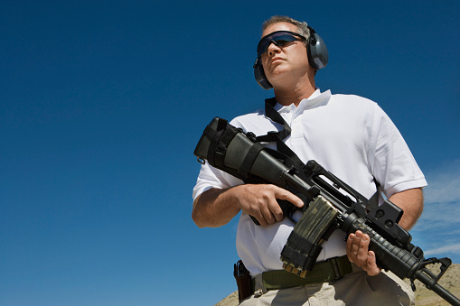 Man holding machine gun at firing range, low angle view