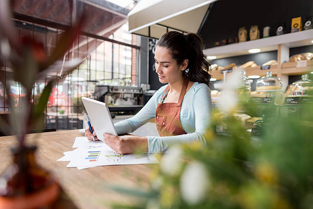 woman doing the books at a restaurant - small business built structure retail imagens e fotografias de stock