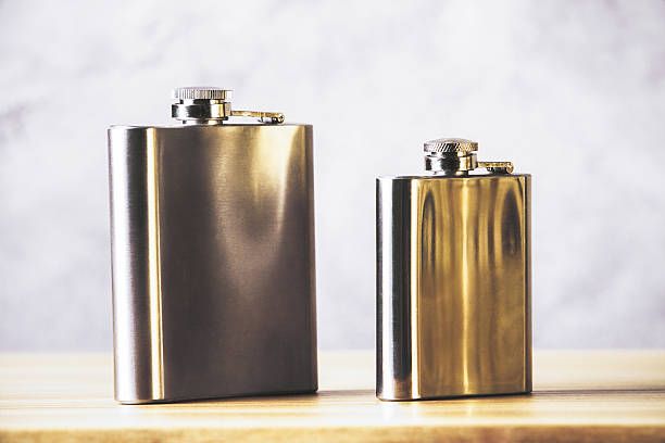 Flasks on wooden table Two steel flasks on wooden table and with concrete wall in the background. Mock up hipflask stock pictures, royalty-free photos & images