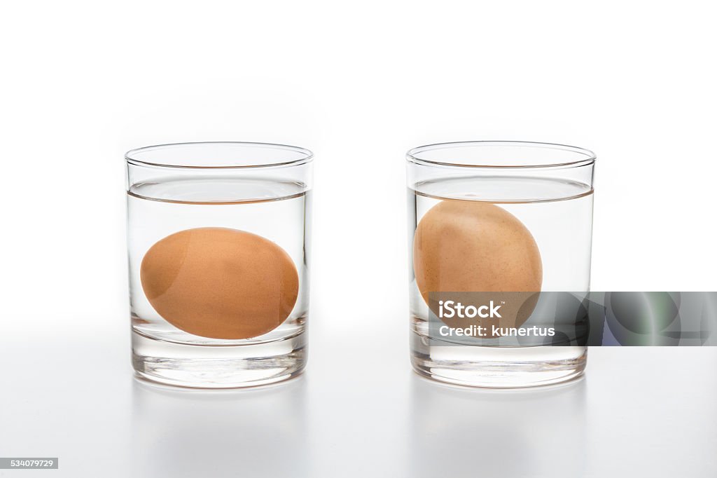 Test for Fresh and rotten eggs Two glasses of water with a fresh egg on the left and a rotten egg on the right side isolated on white background 2015 Stock Photo