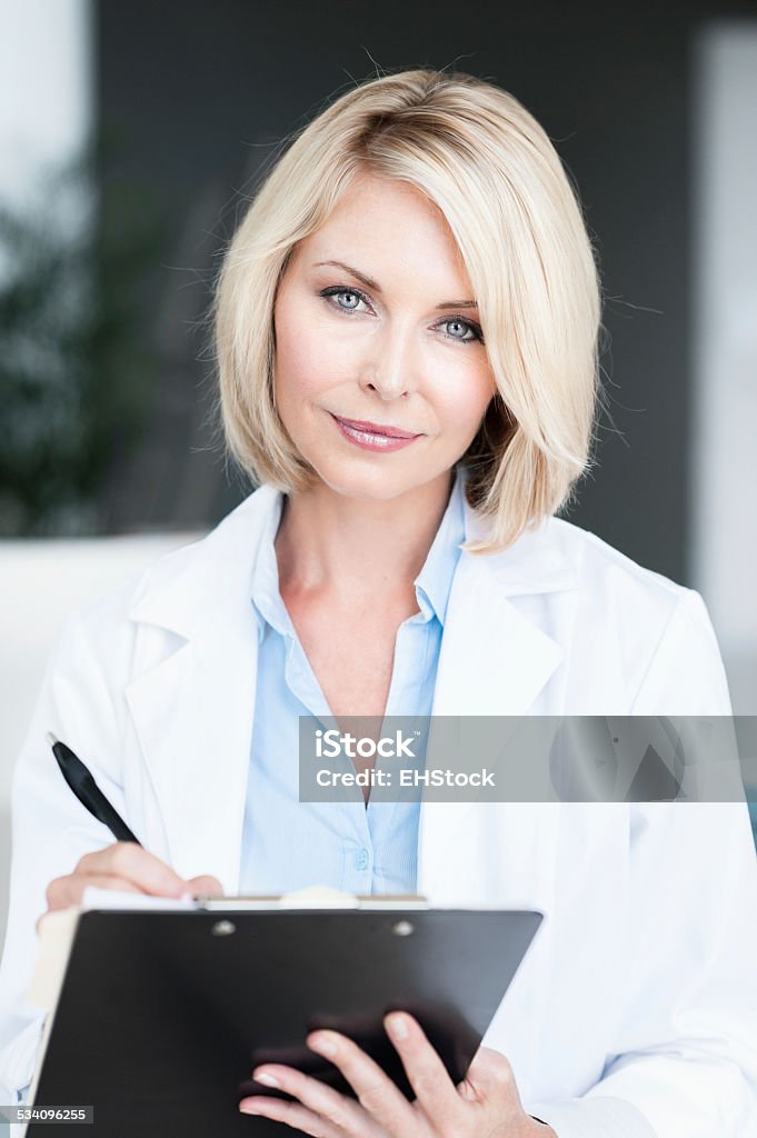 Blonde Woman Doctor in Office with Clipboard Blonde Woman Doctor in Office  20-29 Years Stock Photo