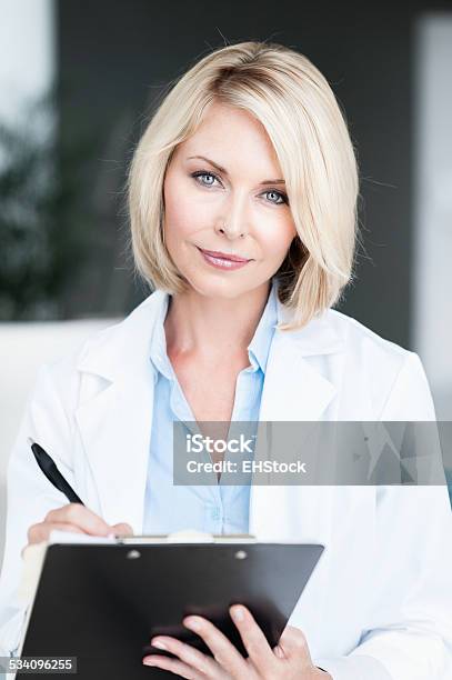 Blonde Woman Doctor In Office With Clipboard Stock Photo - Download Image Now - 20-29 Years, 2015, 30-39 Years