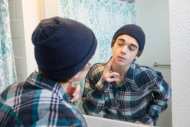 istock Teen boy looking at his face in a bathroom mirror 534101191