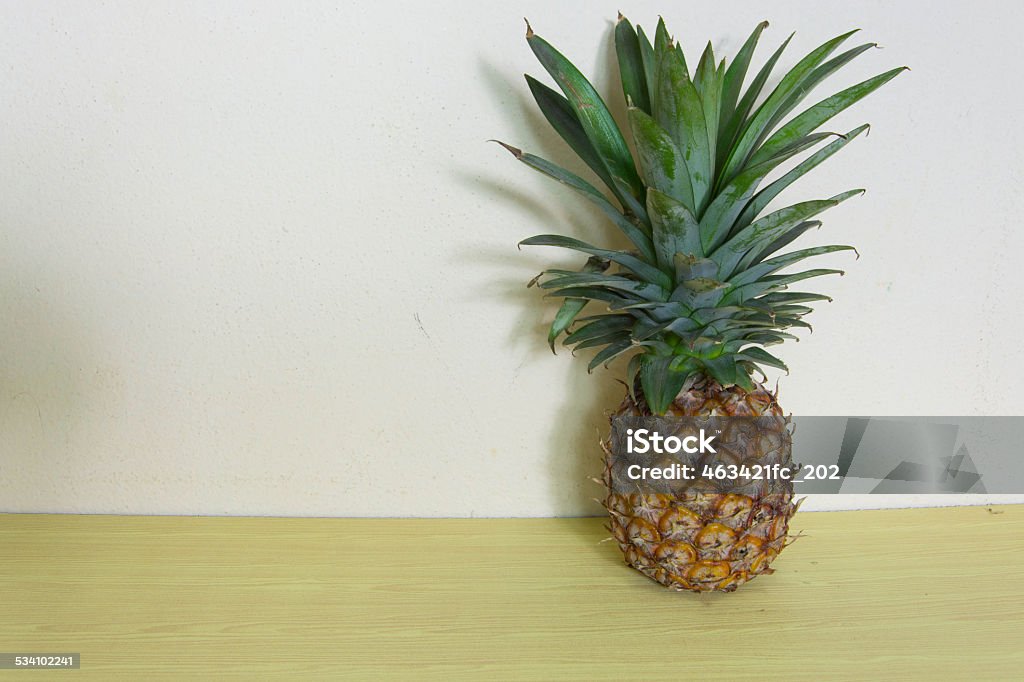 Pineapple on wooden table over grunge background Pineapple on wooden table over grunge background. 2015 Stock Photo