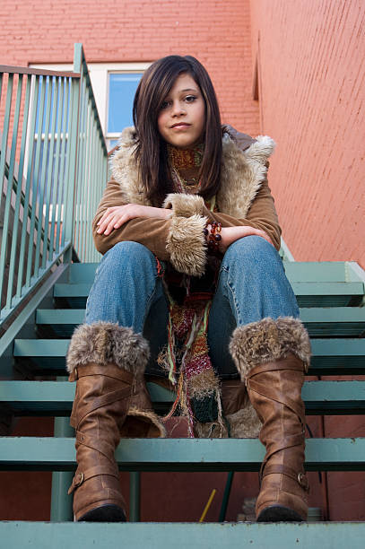 istock Teenager Sitting on Steps in Boots and a Winter Coat 534103763