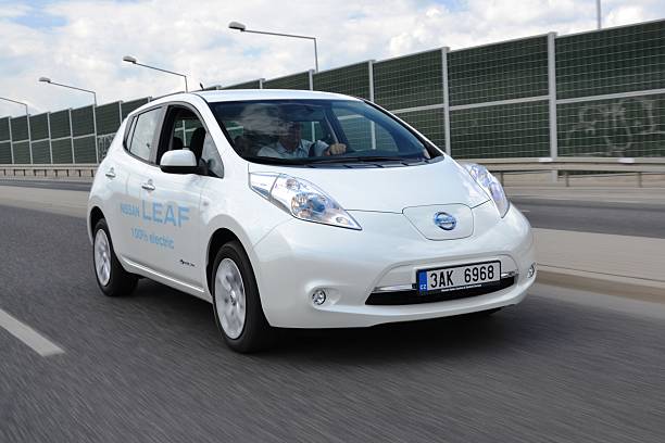 eléctrica coche en movimiento - nissan leaf fotografías e imágenes de stock