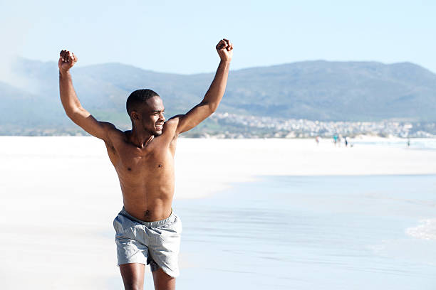 istock Fit young man running on beach with arms raised 534110488
