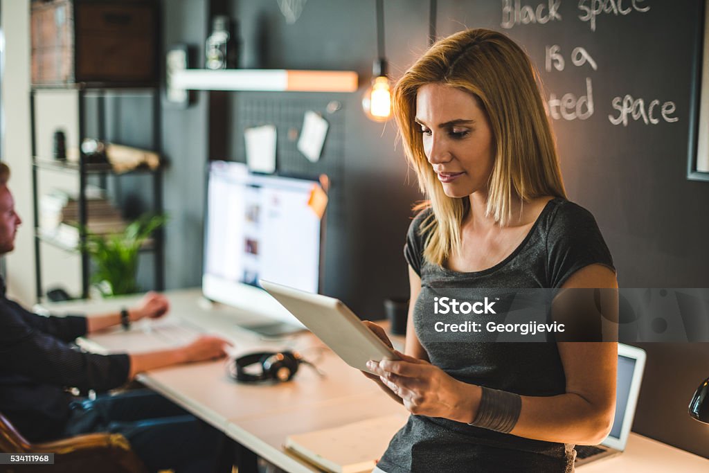 Concentrated on a work Young woman working on a digital tablet. Hipster Culture Stock Photo