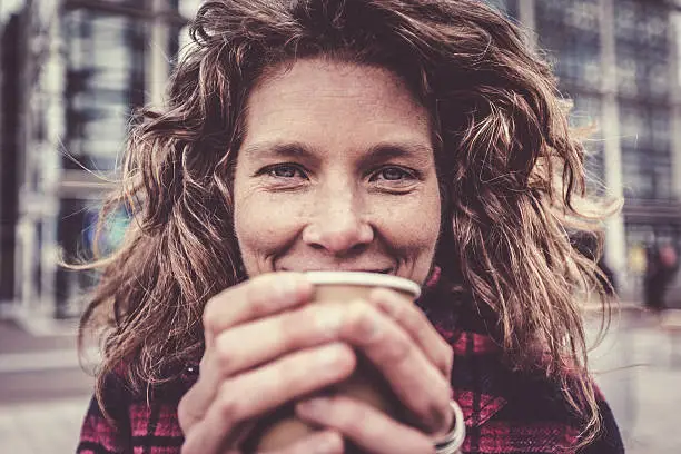 Photo of Woman in her forties warming her hands on coffee cup