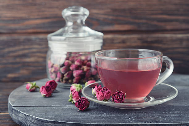 Tea rose flowers Tea rose flowers in glass jar and tea on wooden background pink tea stock pictures, royalty-free photos & images