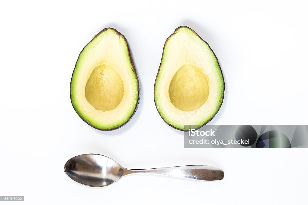 Avocado isoalted on white background Green cut avocado without the seed with silver spoon isolated on white background with free space Avocado Stock Photo