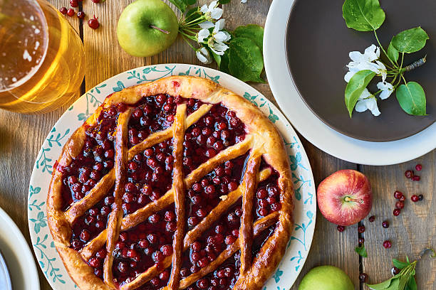 Cherry pie placed near apples and plates on the table 