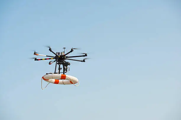 Radio control octocopter (Drone/ UAV) in the air carrying life ring to rescue active drowning victim.