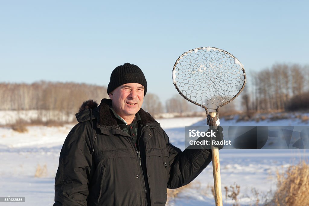 Fisherman with ice fishing skimmer The fisherman posing with hand made ice fishing skimmer, Siberia Activity Stock Photo