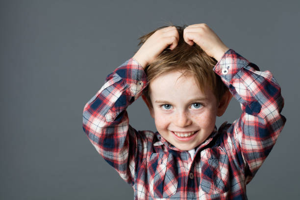 istock smiling young boy scratching hair for head lice or allergies 534124570