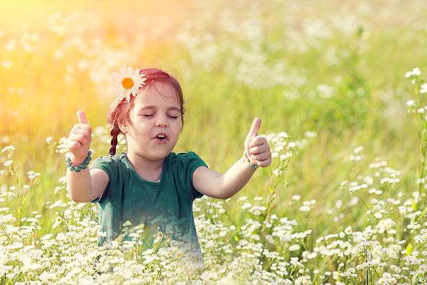 fillette heureuse avec le pouce en l’air sur prairie - hand sign human hand ok sign grass photos et images de collection