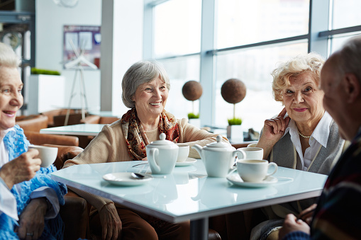 Group of happy seniors having tea and rest in cafe