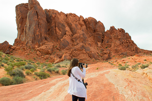 The female tourist taking photos. Girl travel photographer in Valley of Fire State Park, Nevada, USA