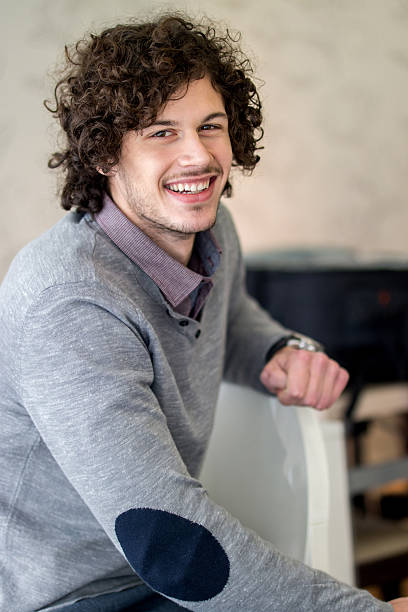 istock Smiling man with curly hair indoors looking at camera. 534129296