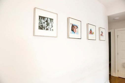 Four framed portraits are hanging on a hallway wall in a home.  One is of the parents and their two young children and the other three are of their two sons.  Taken with a Canon 5D Mark 3 camera.  rm