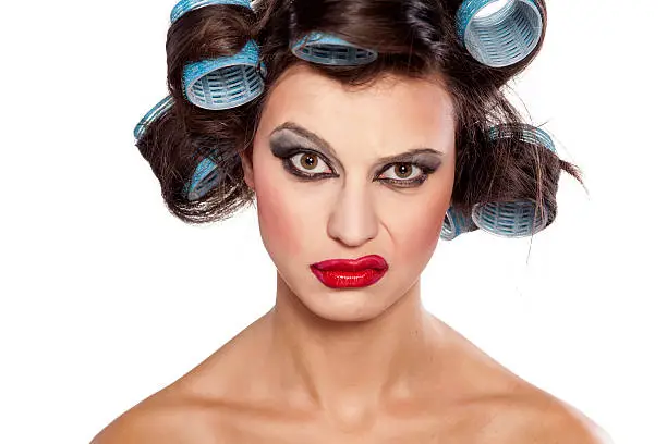 Photo of Funny woman with curlers and bad makeup with questionable gesture