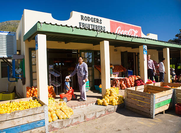 Customers on porch of traditional South African greengrocer's store Cape Town, South Africa - September 17, 2007: Customers browse for produce on the stoop of a traditional South African greengrocer's shop -- one of the last -- on the road between Noordhoek and Kommetjie near Cape Town. This one, a supply store of a kind known in the local dialect as a cafe, is a well-known stop for people heading back after work to their homes in the South Peninsula. kommetjie stock pictures, royalty-free photos & images