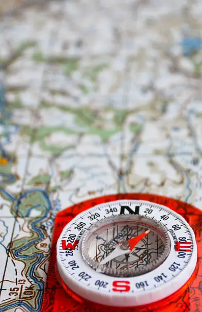 The magnetic compass is located on a topographic map. Equipment for travel - map and compass.