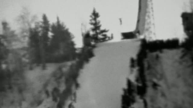1937: Winter snowski jumping competition crowd lines steep hill.