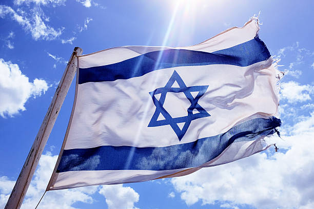Battered and frayed Israeli national flag flying bravely in wind Rather battered and frayed national flag of Israel billowing in the wind against a cloud-strewn sky. A possible metaphor for the country's problems. israeli flag photos stock pictures, royalty-free photos & images