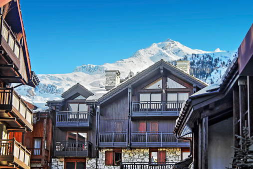 Large apartment building structure, wooden chalet, in Alps ski resort of Val d'Isere in winter season with snow mountain in background. Taken in Massif of Vanoise (Savoie, Rhone-Alpes, France), in Haute Tarentaise Valley.